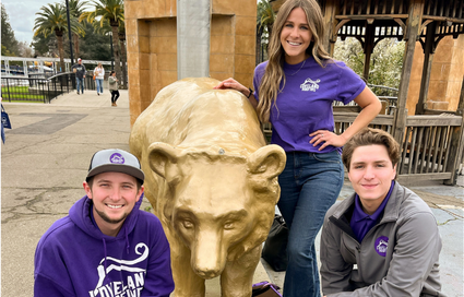 The Loveland Roofing team posing in front of a metallic bear statue
