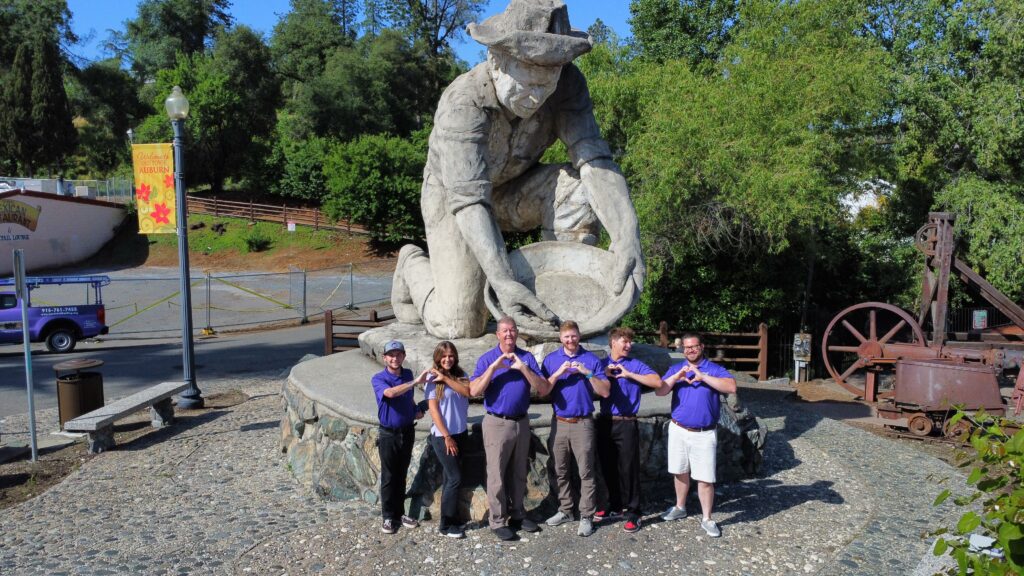 Loveland Roofing team in front of a statue of a prospector.